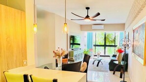 Un soggiorno moderno con zona pranzo, ventilatore a soffitto e TV a parete.