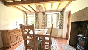 A dining area with a wooden table, chairs, a cabinet, and a fireplace. - 3 Bed in Whatstandwell (oc-h42743) (Whatstandwell)