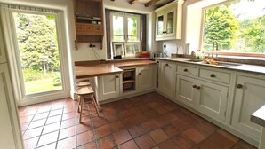 A kitchen with a wooden countertop, white cabinets, and a view of greenery outside. - 3 Bed in Whatstandwell (oc-h42743) (Whatstandwell)