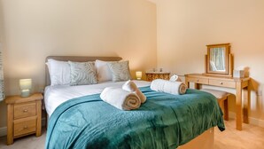 Een hotelkamer met een bed, nachtkastjes, een kaptafel en een spiegel.