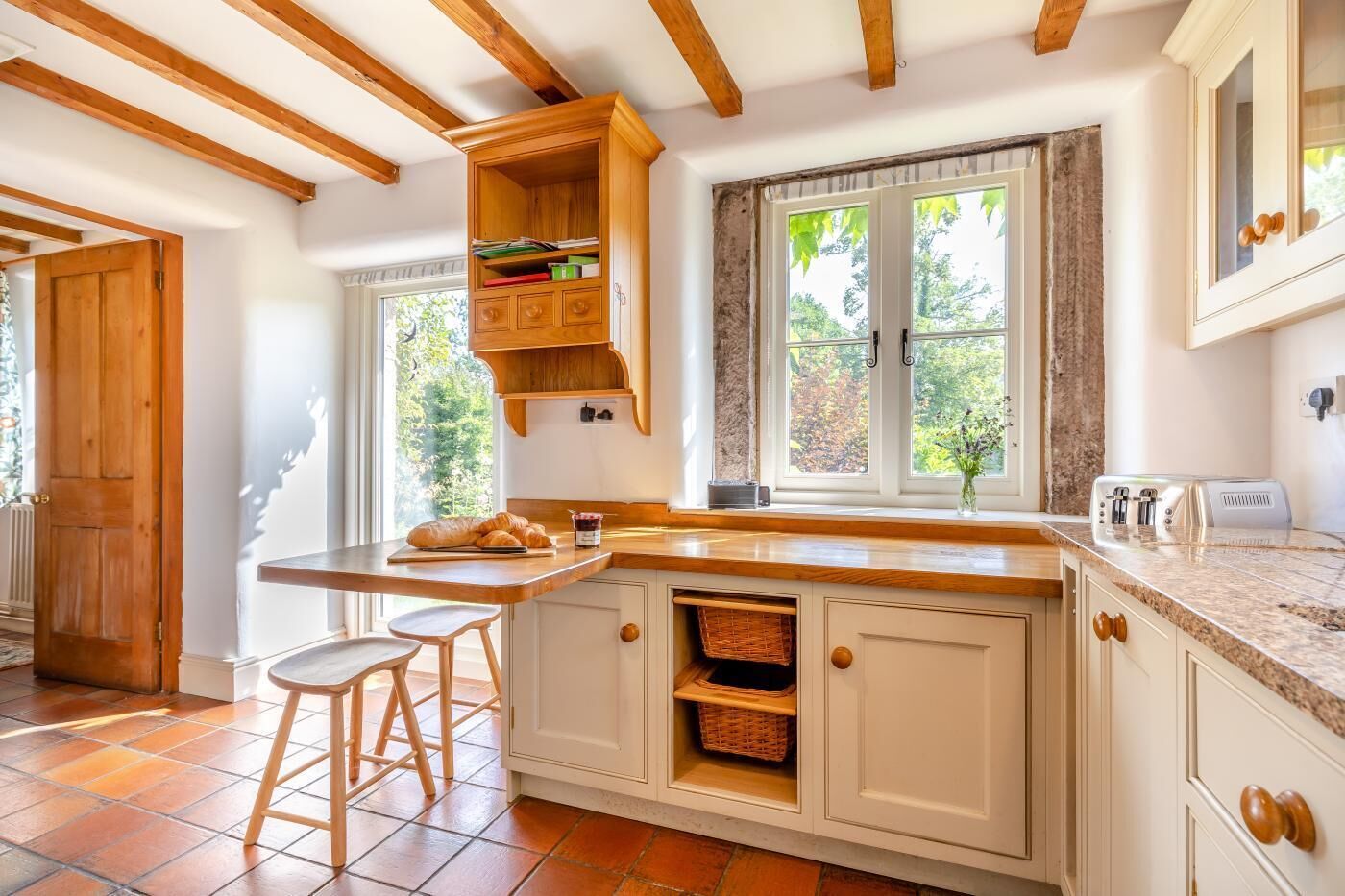 Een keuken met een houten kookeiland, witte kastjes en een raam met uitzicht op groen.