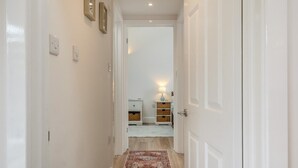 A hallway with a white door, a light switch, and a wall-mounted light fixture. - 2 Bed in Cowes (oc-t44721) (Rew Street)