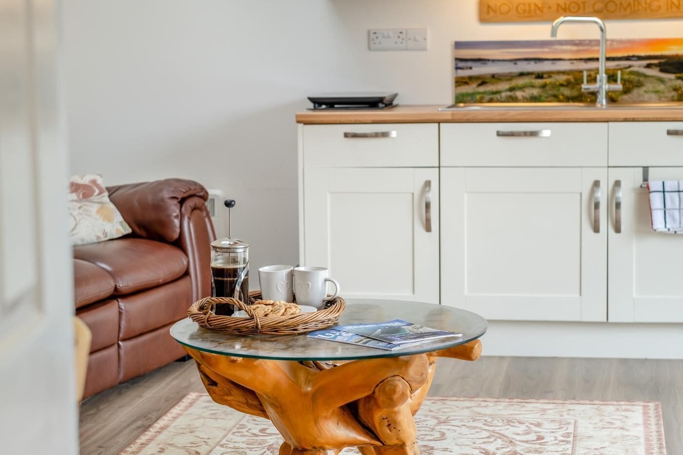 A cozy living area with a coffee table, a sofa, and a kitchen in the background.