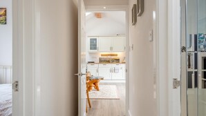 A hallway leading to a kitchen with white cabinets, a dining table with chairs, and a rug. - 2 Bed in Cowes (oc-t44721) (Rew Street)
