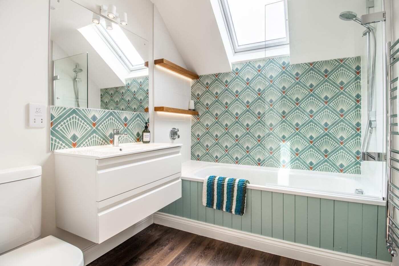 Een moderne badkamer met dakraam, een vrijstaand bad en een wastafelmeubel met spiegel.