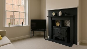 Een kamer met een open haard, een televisie en een raam met uitzicht op een bakstenen gebouw.