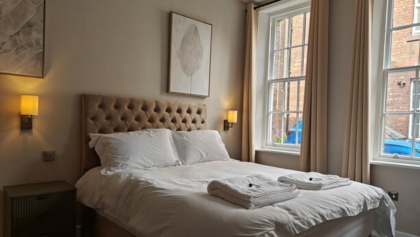 A neatly made bed with white linens, a tufted headboard, and a framed artwork above it. - 2 Bed in Carlisle (oc-a42762) (Carlisle)