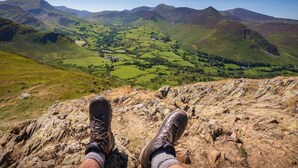 A person seated on a rocky ledge overlooking a valley with rolling hills and a clear sky. - 3 Bed in Carlisle (oc-a42763) (Carlisle)