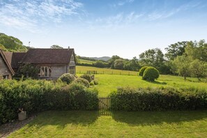 Ein ländliches Haus mit Garten, Holzzaun und blauem Himmel.