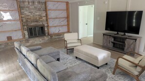 A living room with a sectional sofa, a TV, a fireplace, and a patterned rug. - Spacious 4BR Home · Near IAH · Self Check-In (Spring)
