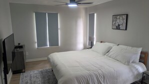 A bedroom with a bed, a ceiling fan, a TV, and a window. - Spacious 4BR Home · Near IAH · Self Check-In (Spring)