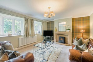 A living room with a fireplace, leather sofas, a glass coffee table, and a television. - 3 Bed in Scalby (oc-s42779) (Scalby)