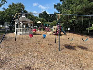 A playground with swings, a gazebo, and a slide.