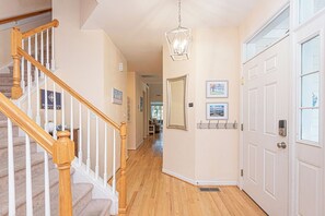 A hallway with a wooden staircase, a hanging light fixture, and a door with a window. - Pond View Bear Trap Home- 4BR 3.5BA - Screened Porch - Near Bethany Beach & Golf (Ocean View)