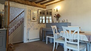 Une pièce avec un escalier, une table à manger avec des chaises, un radiateur et un miroir.