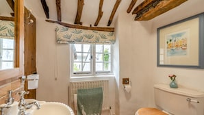 A bathroom with a wooden ceiling, a window with a patterned valance, a radiator, a toilet, and a sink with a mirror. - 3 Bed in Wrafton (oc-t44230) (Braunton)