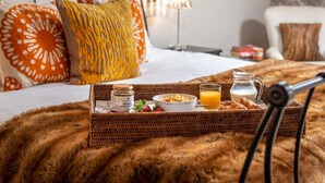Ett fint uppdukat frukostbricka på en säng med ett mjukt täcke, en kudde, en lampa och en vägg med en intressant yta.