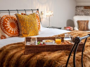 A neatly made breakfast tray on a bed with a fluffy blanket, a pillow, a lamp, and a wall with a textured design. - 1 Bed in Brecon (oc-42936) (Llanfrynach)