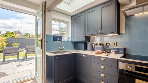 Una cocina moderna con armarios oscuros, horno empotrado y una ventana grande con vistas a un jardín.