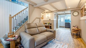Una sala de estar con sofá, una escalera, un comedor y una cocina.