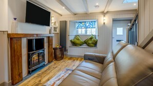Una sala de estar con chimenea, sofá y televisor montado en la pared.