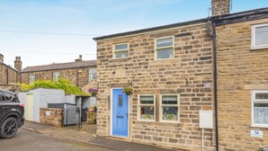 A stone house with a blue door, a small garden, and a parked car. - 2 Bed in East Morton (oc-m42778) (East Morton)
