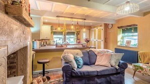 A cozy living room with a fireplace, a sofa, a dining area, and a kitchen visible through an open door. - 2 Bed in East Morton (oc-m42778) (East Morton)
