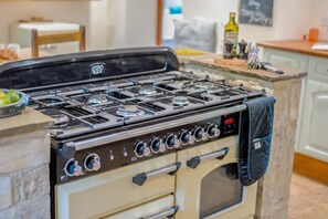 A kitchen with a stove, oven, and various kitchen utensils. - 3 Bed in Duntisbourne Abbots (oc-f42787) (Duntisbourne Abbots)