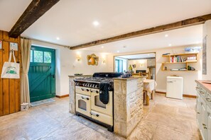 A kitchen with a central island, a stove, and a refrigerator. - 3 Bed in Duntisbourne Abbots (oc-f42787) (Duntisbourne Abbots)