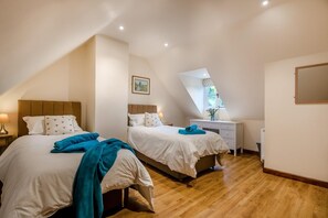 A bedroom with two beds, a desk, and a window. - 3 Bed in Duntisbourne Abbots (oc-f42787) (Duntisbourne Abbots)