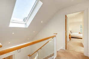 Ein modernes Interieur mit einer Treppe, einem Oberlicht und einem Schlafzimmer mit Bett und Nachttisch.