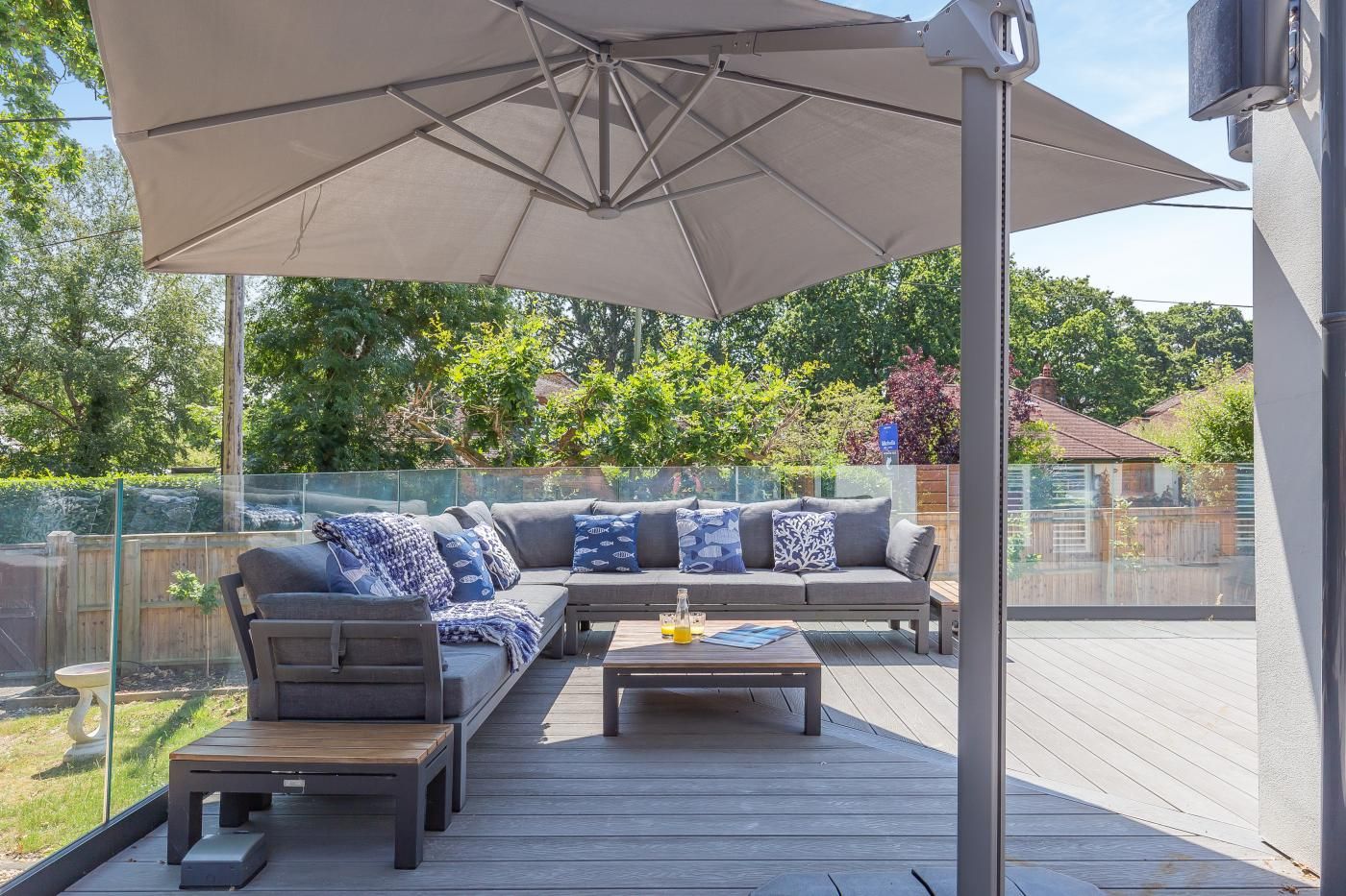An outdoor deck with a sofa, coffee table, and umbrella.