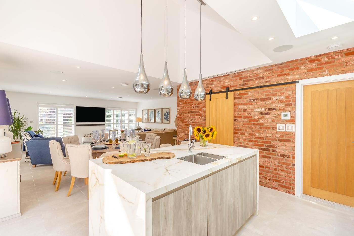 A modern kitchen with a marble countertop, a built-in sink, and hanging pendant lights.