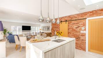 A modern kitchen with a marble countertop, a built-in sink, and hanging pendant lights.
