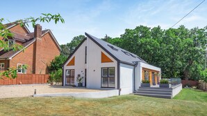 A modern two-story house with a sloped roof, a brick chimney, and a well-maintained lawn. - 4 Bed in New Milton (oc-b44761) (New Milton)