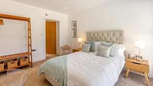 A bedroom with a bed, bedside tables, a wooden wardrobe, and a chair. - 4 Bed in New Milton (oc-b44761) (New Milton)