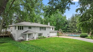 A two-story house with a covered porch, a garage, and a swimming pool in the background.