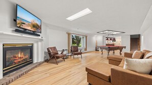 A modern living room with a flat-screen TV, fireplace, pool table, and comfortable seating.