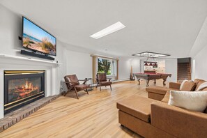 Una sala de estar moderna con televisor de pantalla plana, chimenea, mesa de billar y asientos cómodos.