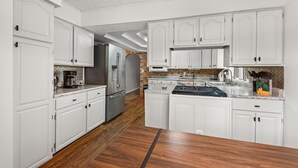 A kitchen with white cabinets, a wooden floor, and a central island.