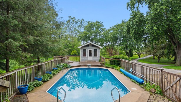 A rectangular pool with a wooden deck, surrounded by a wooden fence, and a small building in the center.