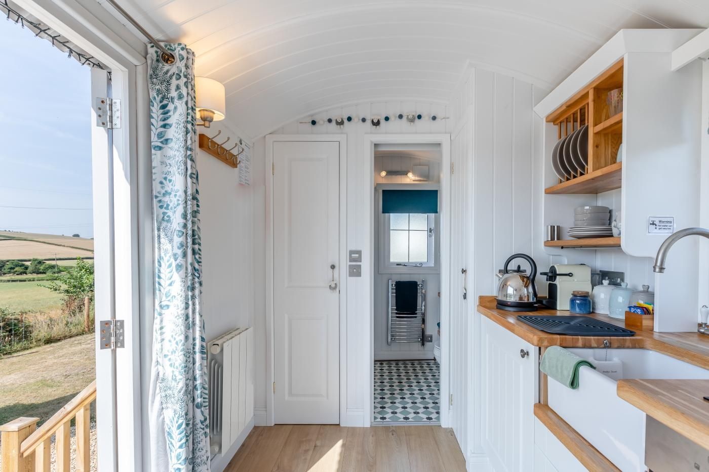 A compact kitchen with white cabinetry, a wooden countertop, and a view of the outdoors.