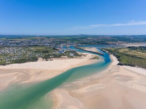 Vue aérienne d’une zone côtière avec une rivière, des plages de sable et une zone résidentielle.