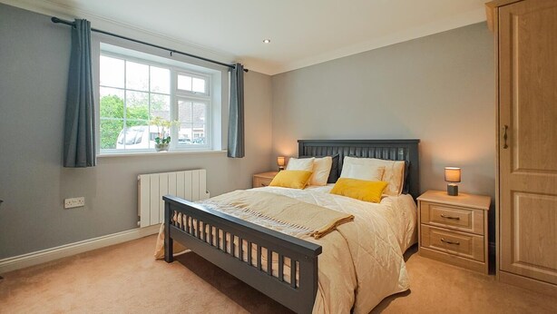 A bedroom with a bed, bedside tables, a window with curtains, a radiator, and a wardrobe. - 1 Bed in Winterborne Zelston (oc-r43274) (Winterborne Zelston)