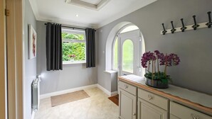 A hallway with a radiator, a window with curtains, a potted plant, and a coat rack. - 1 Bed in Winterborne Zelston (oc-r43274) (Winterborne Zelston)