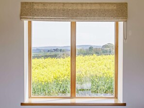 A window with a view of a yellow flowering field, a wooden window frame, and a patterned valance. - 1 Bed in Bridgwater (oc-36423) (North Petherton)