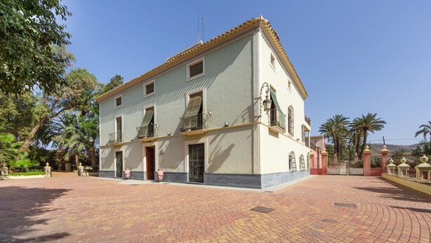 A two-story building with a tiled roof, a paved courtyard, and a gated entrance. - Country House 'La Florida' with Shared Pool, Wi-Fi and Air Conditioning (Los Menas)