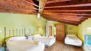 A room with two single beds, a wooden ceiling, a door, and a wall-mounted air conditioning unit. - Country House 'La Florida' with Shared Pool, Wi-Fi and Air Conditioning (Los Menas)