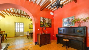 A room with a red wall, a wooden ceiling, a piano, and a door leading to another room. - Country House 'La Florida' with Shared Pool, Wi-Fi and Air Conditioning (Los Menas)