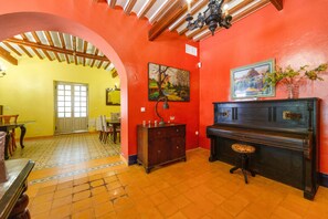 A room with a red wall, a wooden ceiling, a piano, and a door leading to another room. - Country House 'La Florida' with Shared Pool, Wi-Fi and Air Conditioning (Los Menas)